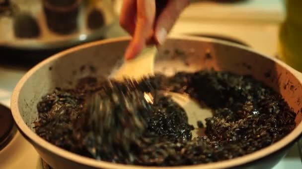 Mieszanie czarnego risotto z łopatką w patelni na kuchence — Wideo stockowe