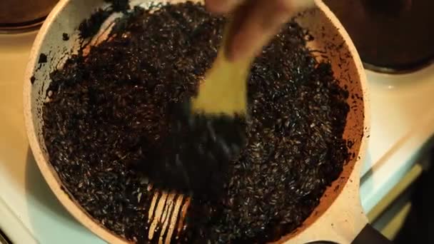 Míchání černé risotto ingredience s špachtle v pánvi. Italské jídlo