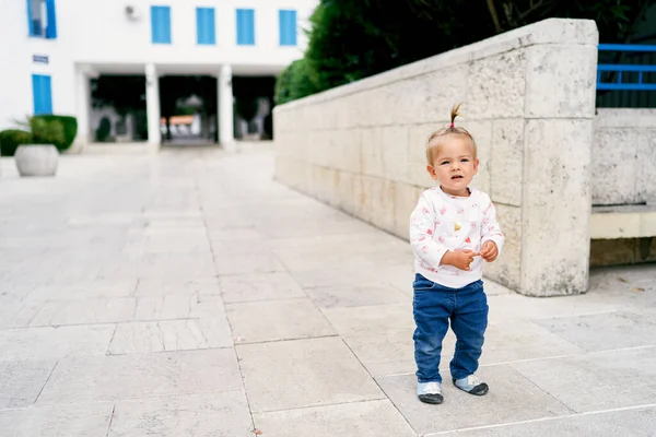 Bambina si trova su una piastrella nel cortile di una casa vicino alla recinzione — Foto Stock