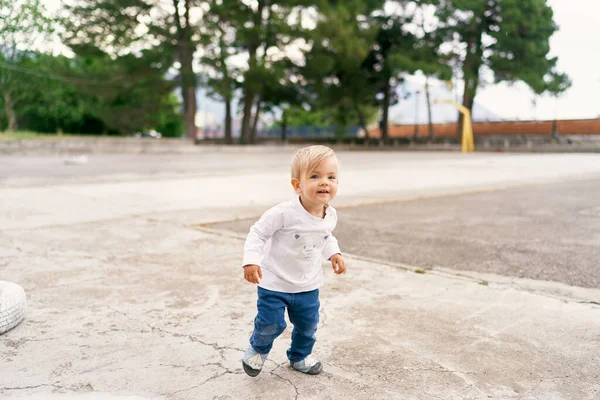 Uśmiechnięte dziecko stoi na betonowym placu zabaw — Zdjęcie stockowe