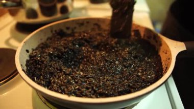 Siyah risottoyu tavada spatulayla karıştırmak. İtalyan deniz ürünleri