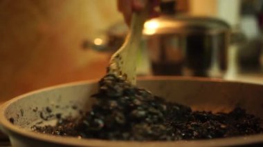 Acılı tavada sebze ve pilav ile sosu karıştırmak. Siyah risotto yapma işlemi