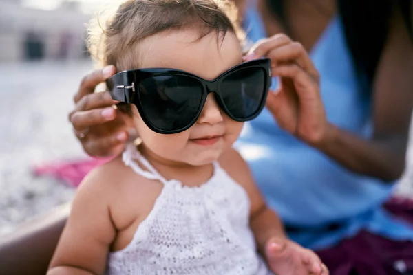 Мама поставила великі сонцезахисні окуляри на маленьку дівчинку. — стокове фото