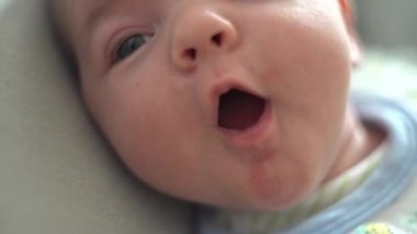 Çocuk yatağa uzanır ve ağzını açar. Yakın plan.