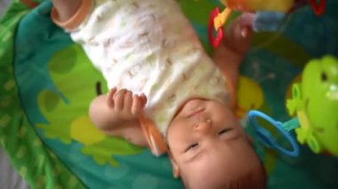 Bebek paspasa uzanıp oyuncaklara eliyle dokunuyor.