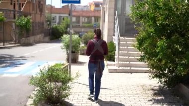 Askıda yeni doğmuş bir bebeği olan bir anne şehirde kaldırım boyunca yürür. Arka plan