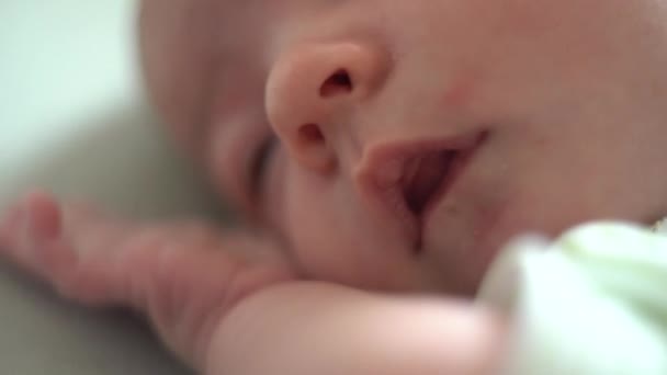 Criança deita-se na cama e toca o rosto com as mãos — Vídeo de Stock