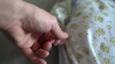 Babam yeni doğan bebeğin küçük parmaklarını eliyle okşar.