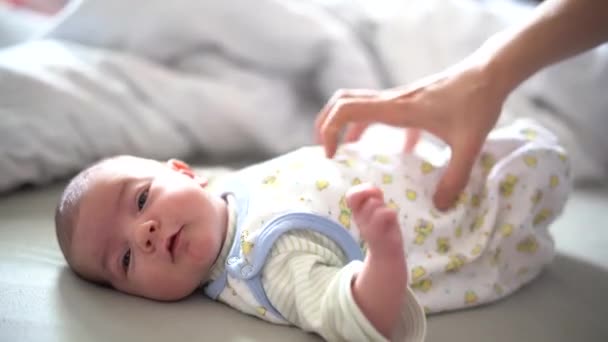 Mama kietelt de buik van de baby liggend op het bed — Stockvideo