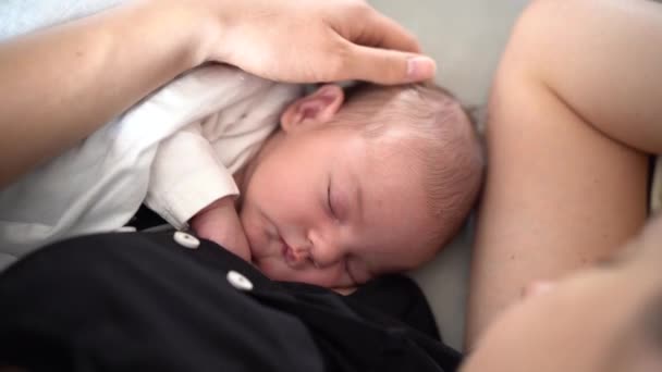 Mama głaszcze głowę śpiącego noworodka — Wideo stockowe