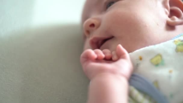 El bebé yace en la cuna, bosteza y toca su cara con su mano — Vídeos de Stock