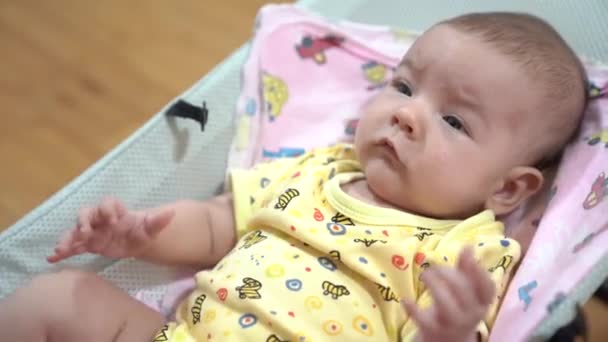 Pasgeboren schommels in een baby schommelstoel — Stockvideo