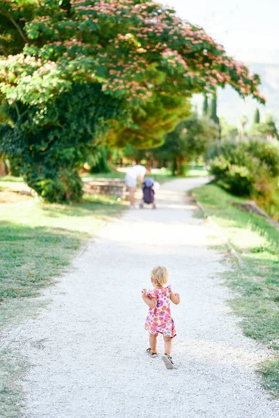 Menina caminhando ao longo do caminho de cascalho no parque verde — Fotografia de Stock