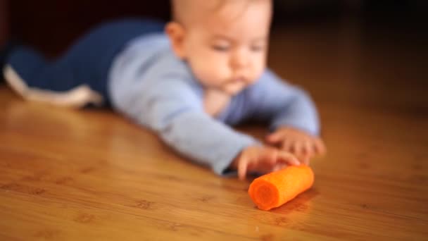 Baby crawls towards a carrot lying on the floor — Stock Video