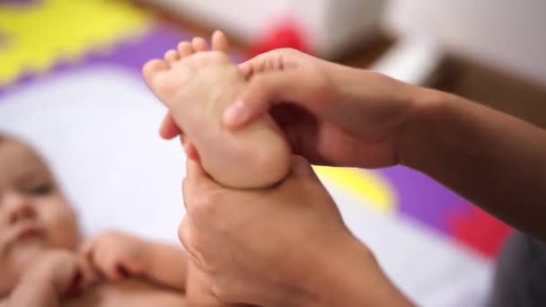 Mujer masajeando el pie de un bebé mentiroso — Vídeos de Stock