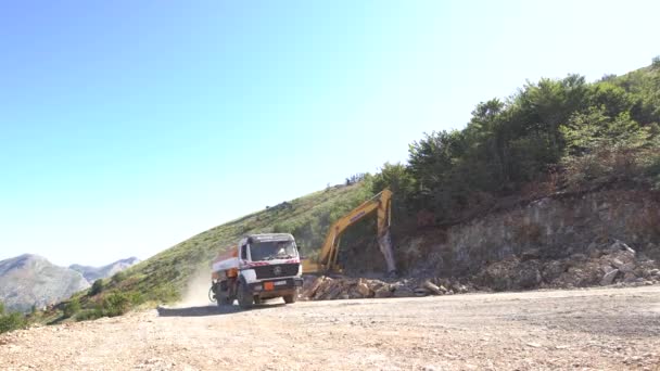 Camion conduit par une machine de forage travaillant sur le côté en pierre de la montagne. — Video