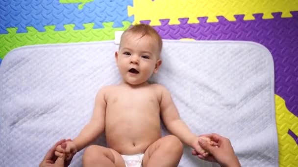 Mãe treme e estica os braços do bebê deitado — Vídeo de Stock