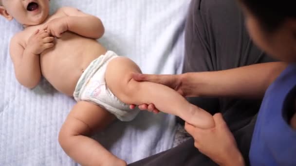 Femme massages la jambe d'un enfant souriant couché — Video