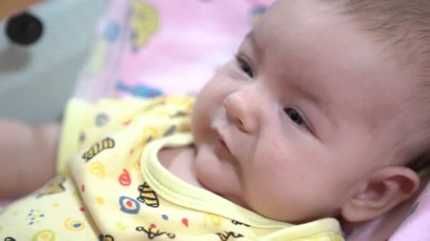 Newborn is mischievous and makes faces in a baby rocking chair — Stock Video