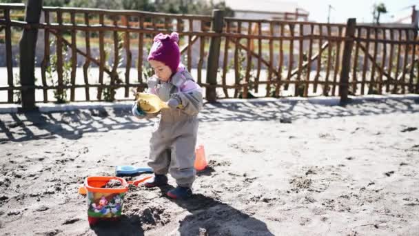 Niña jugando con arena, pala y cubo en el patio — Vídeos de Stock