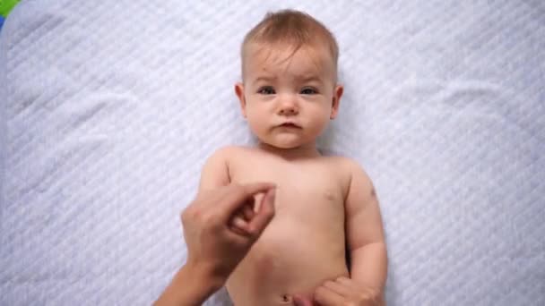 Mama podnosi ręce kłamliwego dziecka naprzemiennie — Wideo stockowe