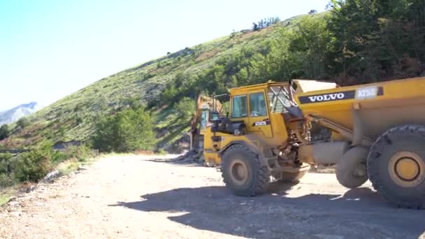 Lastwagen fahren auf eine Bohrmaschine zu, die die Steinseite des Berges anbohrt — Stockvideo