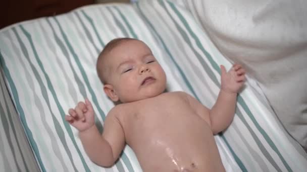 Bebé recién nacido acostado en la cama se masajea la barriga — Vídeos de Stock