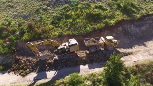 Graafmachine laadt aarde op een vrachtwagen in de bergen — Stockvideo