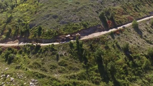 Excavadora expande la carretera en la pendiente de la montaña y pone piedras en el camión — Vídeo de stock