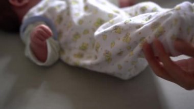 Yeni doğmuş bebek yatağa uzanıyor ve bacaklarını kaldırıyor.