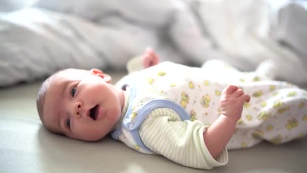 Baby lies on the bed and raises legs and arms — Stock Video