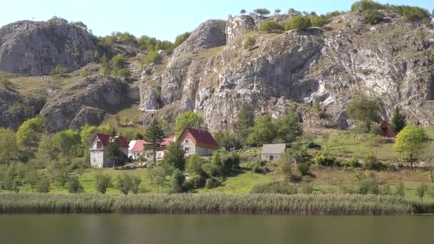 Karadağ 'ın kuzeyindeki bir gölün yakınındaki dağın eteğindeki güzel taş evler. — Stok video