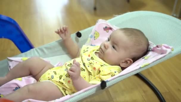 Noworodek szarpie ręce i nogi na dziecięcym fotelu bujanym — Wideo stockowe