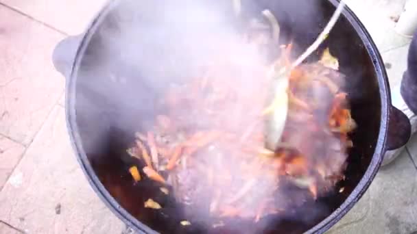 Ανάμιξη καρότων με κρέας σε καζάνι ενώ μαγειρεύετε πιλάφι — Αρχείο Βίντεο