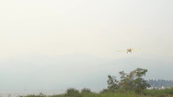 Легкомоторный самолет летит к дымчатым горам — стоковое видео