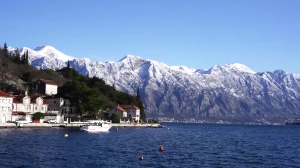 View from the sea to the snow-capped mountains and buildings on the coast of Perast — Stock Video