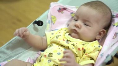 Yeni doğmuş bebek sallanıyor ve sallanan bebek sandalyesinde kollarını sallıyor