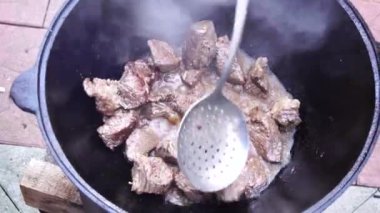 Özbek pilavı için benekli kaşıkla et karıştırma