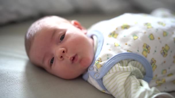 Pasgeborene ligt op het bed en kijkt — Stockvideo