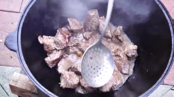 Mezcla de carne para pilaf uzbeko con una cuchara ranurada — Vídeo de stock