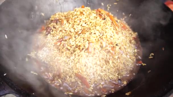 Kochen usbekischer Pilaf mit Reis in einem Kessel — Stockvideo