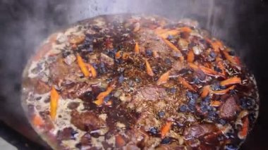 Özbek pilavında haşlanmış kuru üzüm, et, havuç ve soğana baharat eklemek