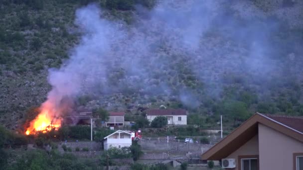 Camión de bomberos está cerca de una casa en llamas en las montañas — Vídeo de stock