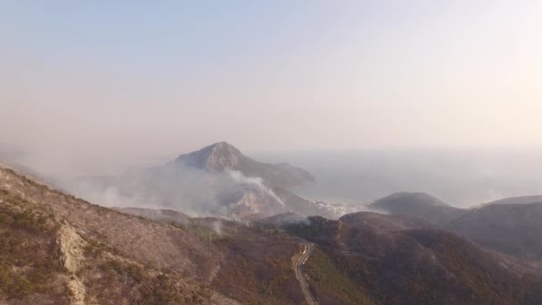 Drone uitzicht op een bergweg en bergen in de waas van bosbranden — Stockvideo