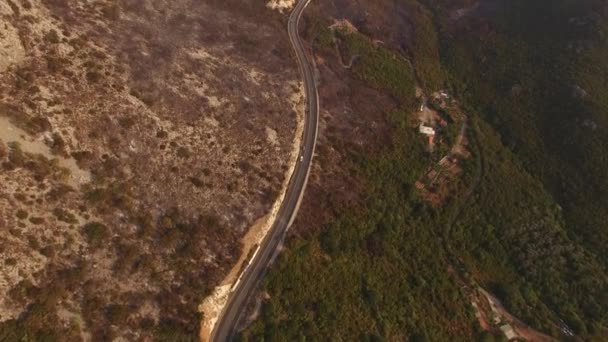 Drone vista de una carretera de montaña con un coche que pasa y montañas después de un incendio — Vídeos de Stock