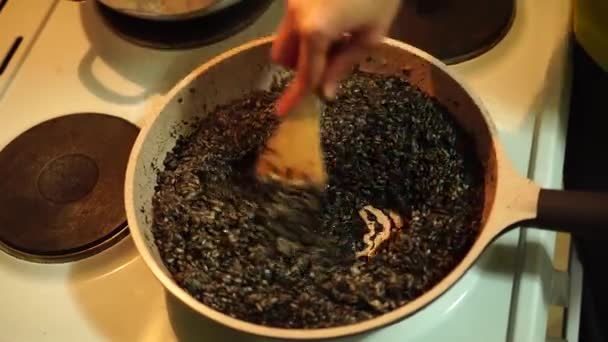 Proces van het bereiden van zwarte risotto in een hete pan — Stockvideo