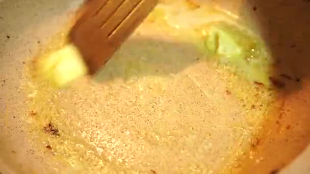 Revuelve trozos de mantequilla en una sartén caliente con una espátula — Vídeo de stock