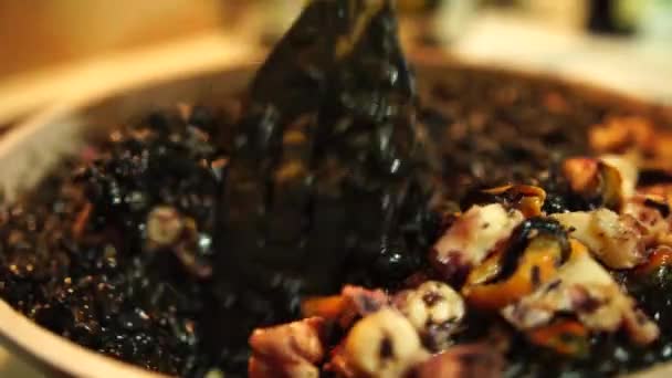 Revuelve risotto negro con mariscos con espátula. Cocinar risotto italiano plato negro. Friendo risotto negro. — Vídeos de Stock