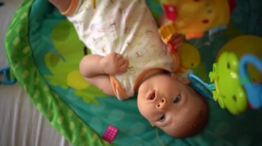 Bebek paspasın üzerinde yatar ve oyuncakları çeker. Üst görünüm