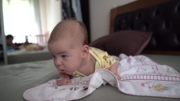 Noworodek próbuje czołgać się po brzuchu na łóżku. — Wideo stockowe